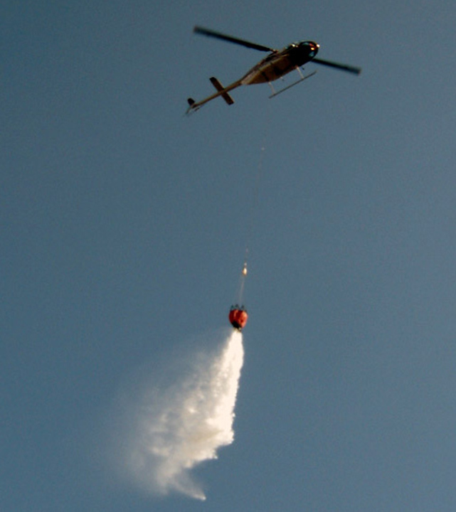 helicopters drop water buckets on forest fires
